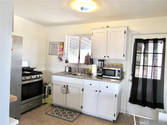 kitchen featuring sink, white cabinets, light tile patterned floors, and appliances with stainless steel finishes