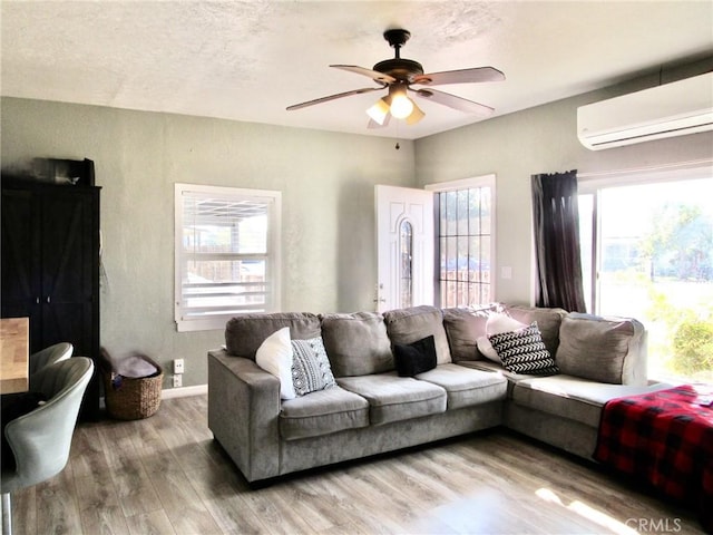 living room with hardwood / wood-style flooring, plenty of natural light, ceiling fan, and a wall unit AC