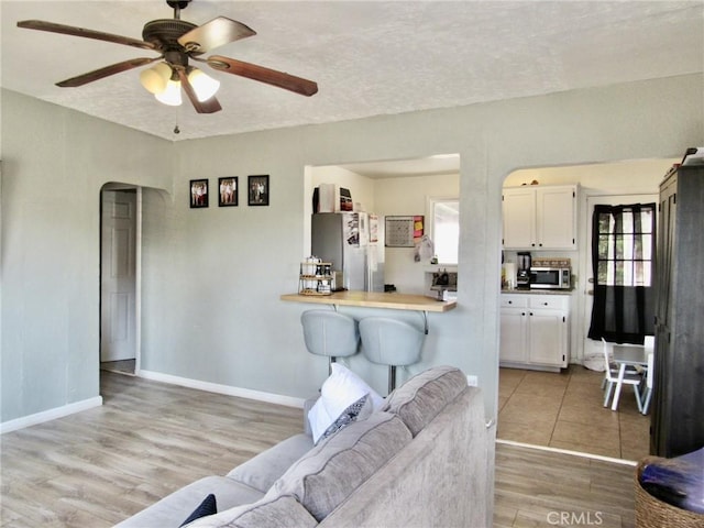 living room with ceiling fan, light hardwood / wood-style floors, and a textured ceiling