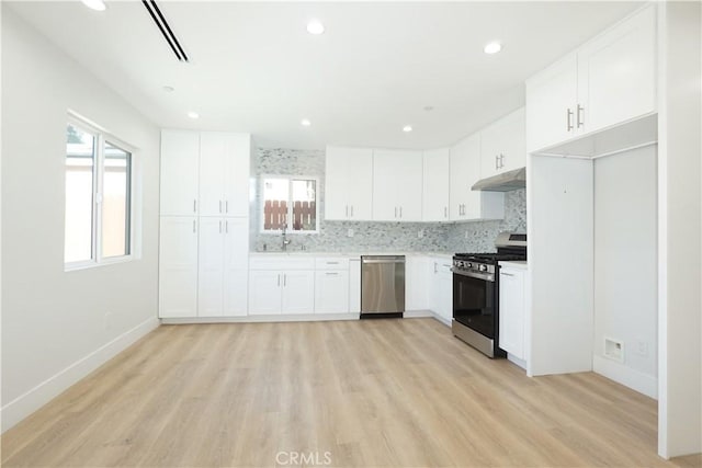 kitchen featuring a wealth of natural light, sink, white cabinets, backsplash, and stainless steel appliances