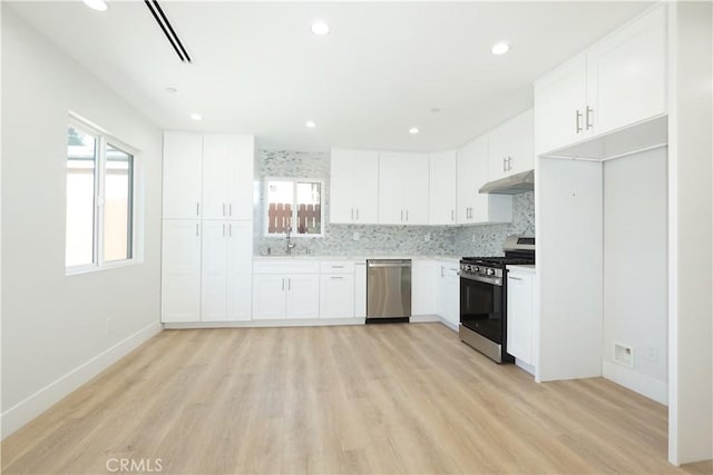 kitchen featuring sink, stainless steel appliances, a wealth of natural light, white cabinets, and decorative backsplash