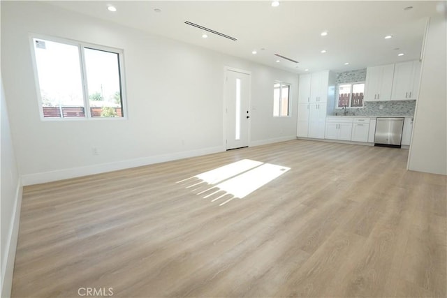 unfurnished living room featuring sink and light hardwood / wood-style flooring