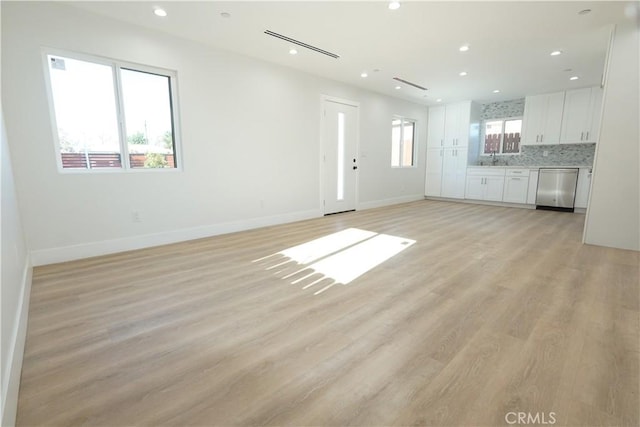 unfurnished living room featuring sink and light hardwood / wood-style flooring