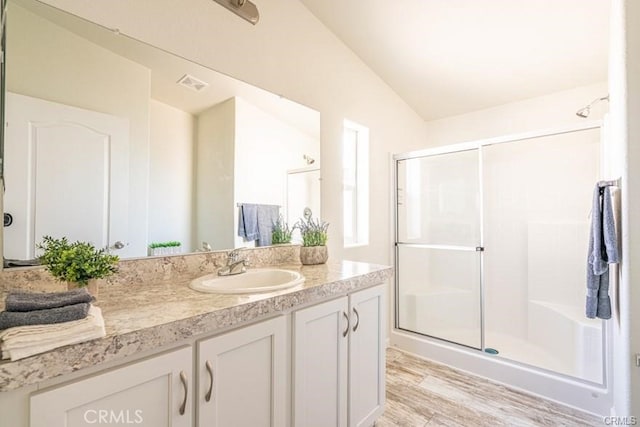 bathroom featuring hardwood / wood-style flooring, vanity, lofted ceiling, and a shower with door