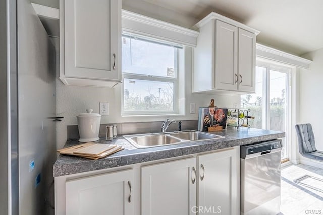 kitchen with a wealth of natural light, dishwasher, white cabinets, and sink