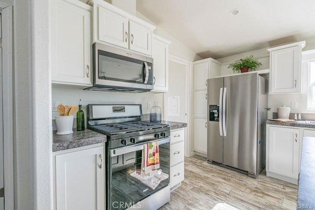 kitchen with light hardwood / wood-style flooring, white cabinets, stainless steel appliances, and lofted ceiling