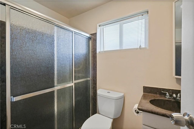 bathroom featuring vanity, toilet, and a shower with shower door