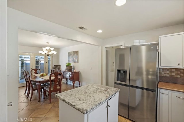 kitchen with pendant lighting, a center island, white cabinets, decorative backsplash, and stainless steel fridge