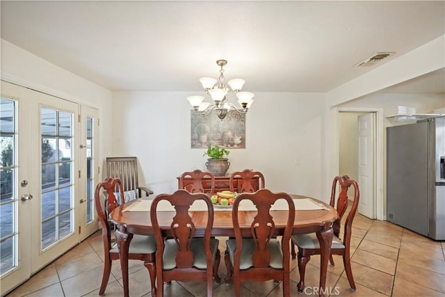 tiled dining room with french doors and a chandelier