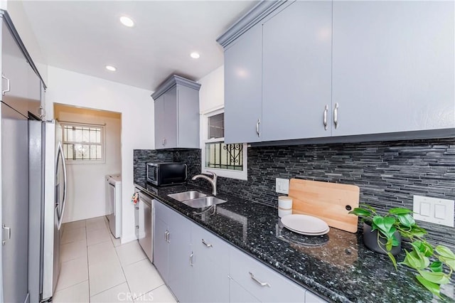 kitchen with sink, washing machine and dryer, gray cabinets, decorative backsplash, and appliances with stainless steel finishes