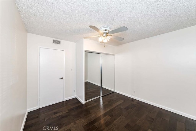 unfurnished bedroom featuring ceiling fan, dark hardwood / wood-style floors, a textured ceiling, and a closet