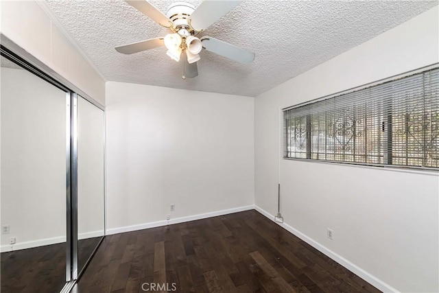 unfurnished bedroom with a textured ceiling, dark hardwood / wood-style floors, a closet, and ceiling fan