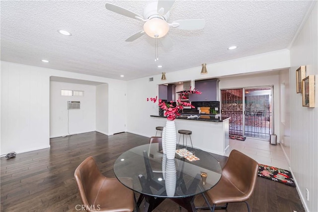 dining space featuring ceiling fan, dark hardwood / wood-style flooring, a textured ceiling, and wooden walls