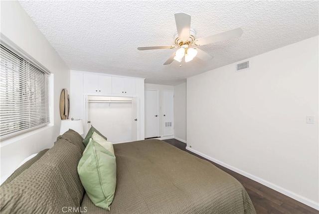 bedroom featuring a textured ceiling, dark hardwood / wood-style floors, a closet, and ceiling fan