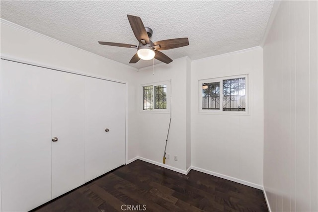 unfurnished bedroom featuring a textured ceiling, ceiling fan, crown molding, dark hardwood / wood-style floors, and a closet