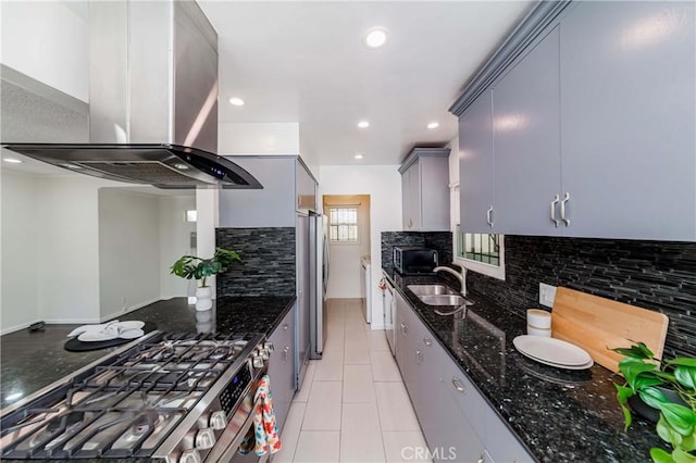 kitchen featuring wall chimney exhaust hood, dark stone countertops, stainless steel appliances, and tasteful backsplash