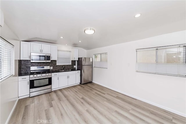 kitchen with decorative backsplash, light hardwood / wood-style flooring, white cabinets, and stainless steel appliances