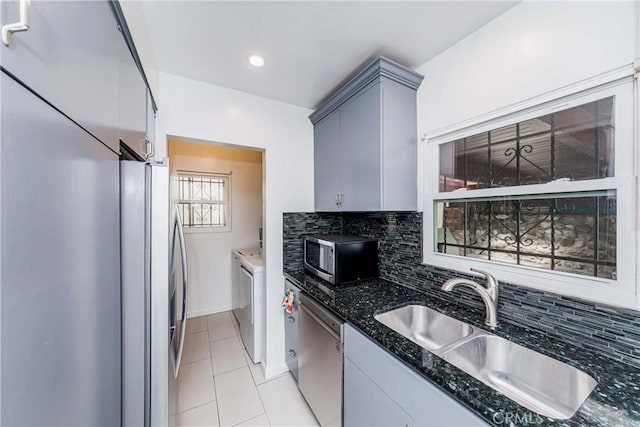 kitchen with washer and clothes dryer, sink, decorative backsplash, gray cabinets, and stainless steel appliances