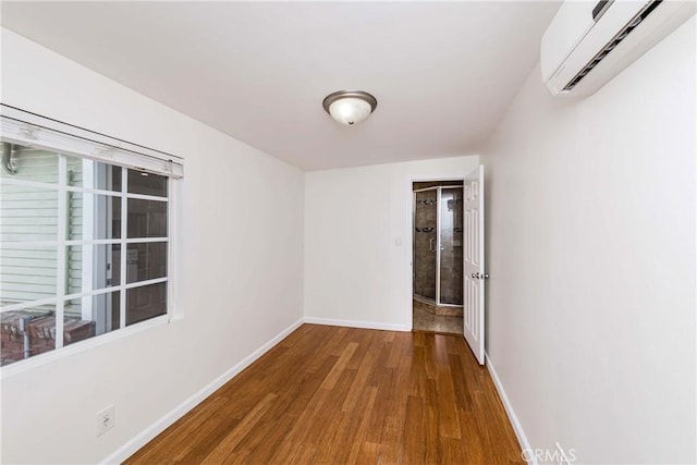 unfurnished room featuring a wall unit AC and hardwood / wood-style flooring