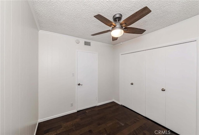 unfurnished bedroom with ceiling fan, ornamental molding, a textured ceiling, dark hardwood / wood-style flooring, and a closet