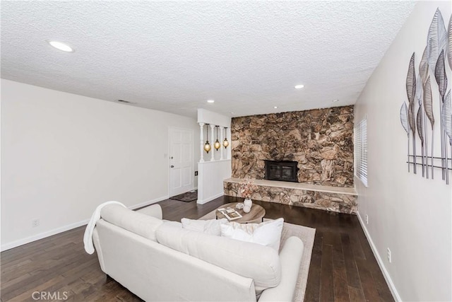 living room featuring a fireplace, a textured ceiling, and dark hardwood / wood-style flooring