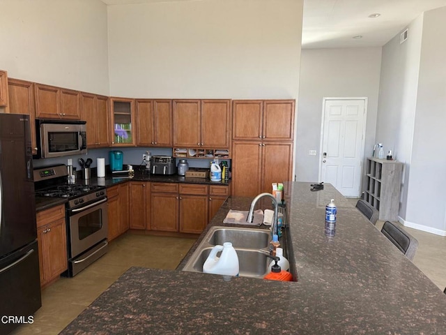 kitchen with light tile patterned floors, a towering ceiling, sink, and stainless steel appliances