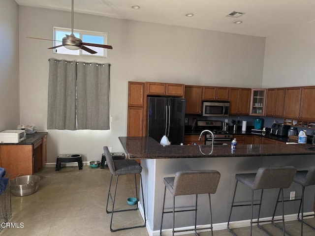 kitchen featuring a breakfast bar area, stainless steel appliances, kitchen peninsula, and ceiling fan