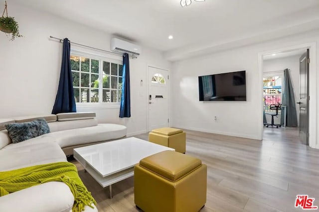 living room featuring light hardwood / wood-style flooring and an AC wall unit