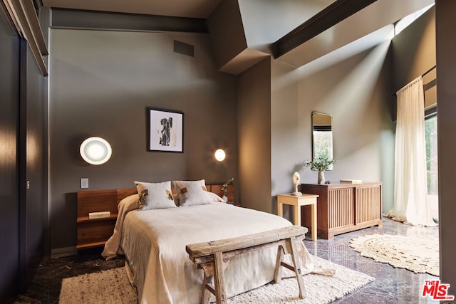 bedroom featuring beam ceiling and a high ceiling