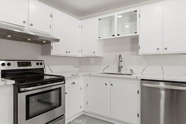 kitchen featuring stainless steel appliances, white cabinetry, sink, and light stone countertops