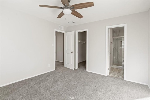 unfurnished bedroom featuring a walk in closet, ceiling fan, carpet, and connected bathroom