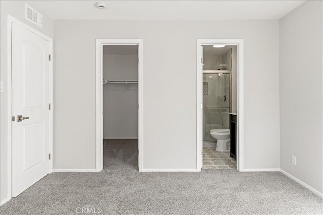 unfurnished bedroom featuring light colored carpet, a closet, a spacious closet, and connected bathroom