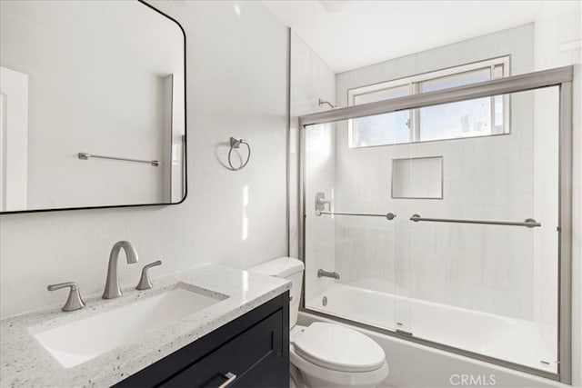 full bathroom with enclosed tub / shower combo, vanity, and toilet