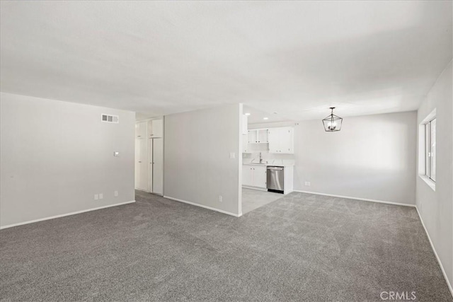 unfurnished living room featuring light colored carpet and an inviting chandelier