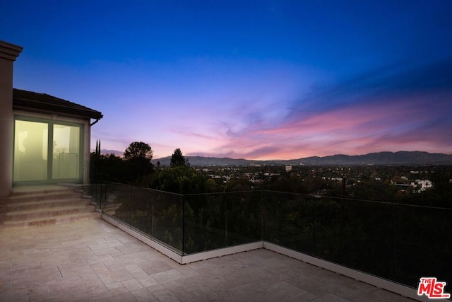 patio terrace at dusk featuring a mountain view