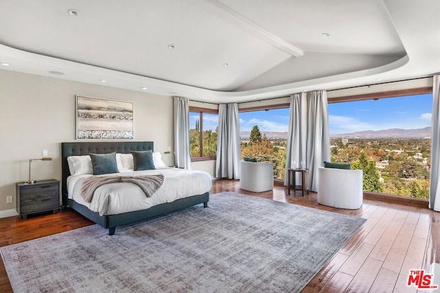 bedroom featuring a mountain view, hardwood / wood-style floors, and lofted ceiling with beams