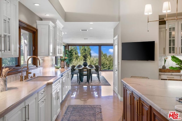 kitchen with white cabinets, decorative light fixtures, and a wealth of natural light