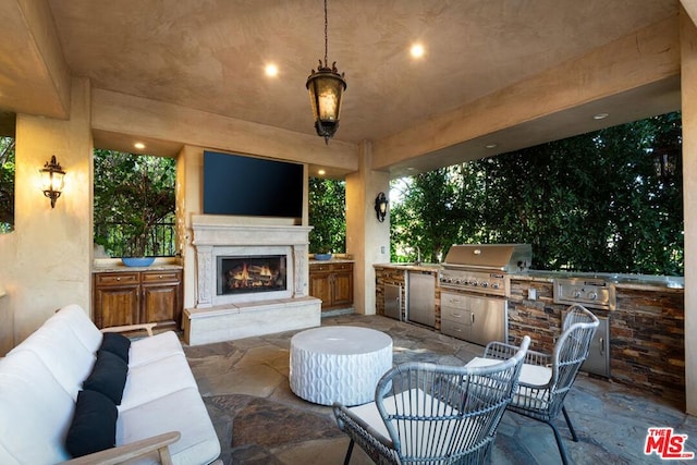 view of patio featuring an outdoor living space with a fireplace, an outdoor kitchen, and a grill