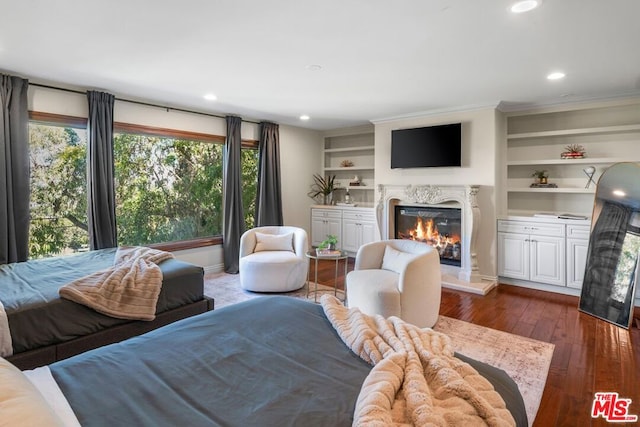 living room with crown molding, a fireplace, dark wood-type flooring, and built in features