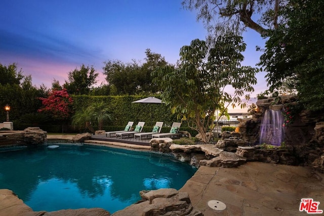 pool at dusk featuring pool water feature