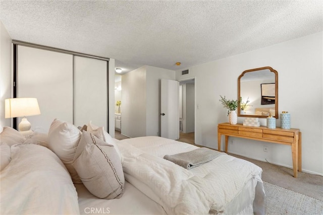 bedroom featuring a textured ceiling, light carpet, and a closet