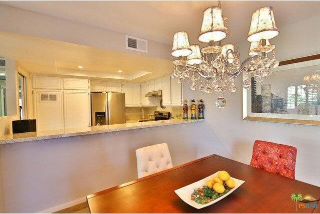 unfurnished dining area featuring a raised ceiling and an inviting chandelier