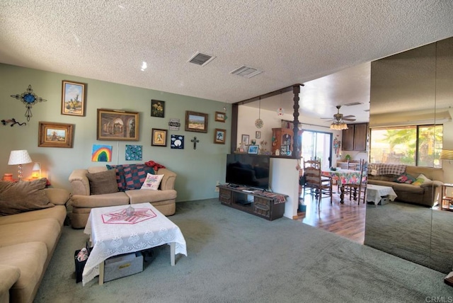 carpeted living room featuring ceiling fan and a textured ceiling