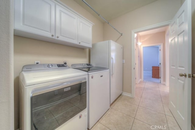 clothes washing area with cabinets, washer and clothes dryer, and light tile patterned flooring