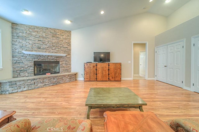 living room with a fireplace, light hardwood / wood-style floors, and high vaulted ceiling