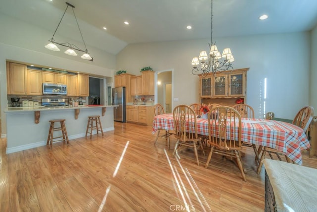 dining area featuring a chandelier, light wood-type flooring, and high vaulted ceiling