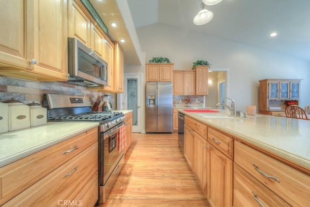 kitchen with sink, light hardwood / wood-style flooring, vaulted ceiling, decorative backsplash, and appliances with stainless steel finishes