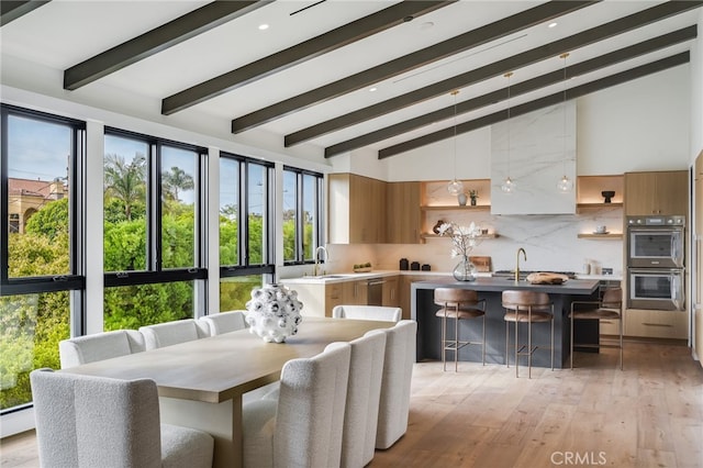 dining area featuring beam ceiling, sink, high vaulted ceiling, and light hardwood / wood-style flooring