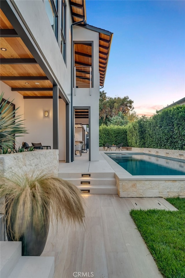 pool at dusk featuring a patio area