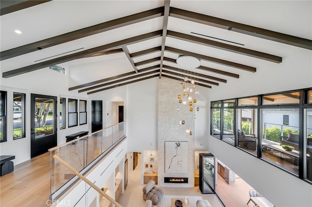 interior space featuring a high end fireplace, high vaulted ceiling, a healthy amount of sunlight, and light wood-type flooring